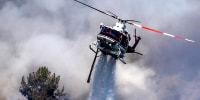 A helicopter makes an aerial drop at the the Chaparral Fire in Murrieta, Calif., on Aug. 29, 2021.