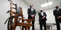 Virginia Gov. Ralph Northam, left, looks over the electric chair in the death chamber at Greensville Correctional Center prior to signing a bill abolishing the penalty in Jarratt, Va., on March 24, 2021.