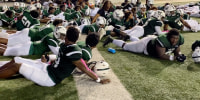 Image: Players lie on the field as they take cover following gunshots during the Vigor versus Williamson football game at Ladd-Peebles Stadium in Mobile