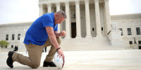 Image: Joe Kennedy kneeling before the Supreme Court.