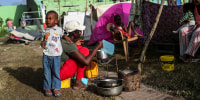 Image: An evacuated woman prepares breakfast in Les Cayes