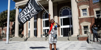 A woman waves a Black Lives Matter flag outside the Glynn County Courthouse, where jury selection in Ahmaud Arbery's murder trial is underway, in Brunswick, Ga., on Oct. 19, 2021.