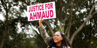 Image: Joy Graves holds a sign outside the Glynn County Courthouse in Brunswick