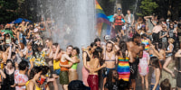 Young people cool off in the fountain at Washington Square Park in New York City on June 27, 2021, during the Pride March.