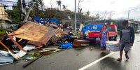 Residentes llevan lo que queda de sus pertenencias mientras caminan junto a casas dañadas por el tifón Rai en la ciudad de Surigao, en el centro de Filipinas, el viernes 17 de diciembre de 2021.