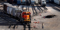 A BNSF rail terminal worker monitors the departure of a freight train, on June 15, 2021, in Galesburg, Ill.