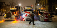 A man walks with a Canada flag in front of a truck as protests against Covid-19 vaccination mandates continue, along Wellington street near the Parliament of Canada, in Ottawa, Ontario, on Feb. 17, 2022.