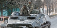Image: Service members of pro-Russian troops are seen atop of an armoured vehicle in Dokuchaievsk