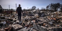 Image: A plainclothes policeman stands among the rubble of destroyed houses in Bohdanivka village, northeast of Kyiv, on April 14, 2022.