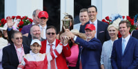 Trainer Eric Reed, center, Jockey Sonny Leon, left, and Owner Rick Dawson, right, celebrate with the trophy after Rich Strike won the 148th running of the Kentucky Derby at Churchill Downs on Saturday in Louisville, Kentucky.