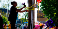 A person tends to a makeshift memorial outside of Tops Friendly Market, in Buffalo, N.Y., on May 15, 2022.