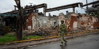 A Russian soldier patrols a destroyed part of the Illich Iron & Steel Works in Mariupol on May 18, 2022.