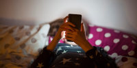 Girl lying on bed at night and using a mobile phone