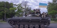Militares ucranianos ondean una bandera que dice en ucraniano 'Gloria a Ucrania' y 'Muerte a los enemigos' mientras viajan sobre un tanque en la región de Kharkiv, en el este de Ucrania, el lunes 16 de mayo de 2022.