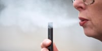A woman exhales a puff of vapor from a Juul pen in Vancouver, Wash., on April 16, 2019.