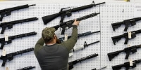 A salesperson takes an AR-15 rifle off the wall at a store in Orem, Utah, on March 25, 2021.