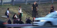 Civilians and police stand together along an area of the New Jersey Turnpike after a bus crash Tuesday.