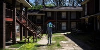 A man carries a case of water through an apartment complex in Jackson, Miss., on March 24, 2022.