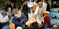 Image: A man distributes free bread during the holy fasting month of Ramadan in front of a bakery in Kabul on April 10, 2022.