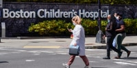 Pedestrians walk past a sign outside the Boston Children's Hospital on Aug. 18, 2022, in Boston.