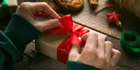 someone adding a red bow to a gift