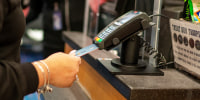 A person uses a credit card at a retail shop