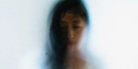 Image: woman face peering through frosted glass