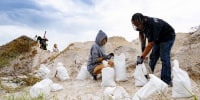 Jontau Hines and Theresa Galluzzo fill up sand bags amid sand dunes as the eastern coast of central Florida braces for Hurricane Ian
