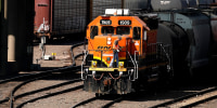 A worker boards a locomotive at a BNSF rail yard on in Kansas City, Kan.