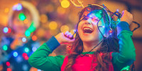 Child laughing while wrapped up in colorful Christmas lights