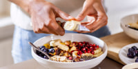 close up of woman making healthy breakfast in kitchen with fruits and yogurt