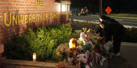 Two people place flowers at a growing memorial in front of a campus entrance sign for the University of Idaho, Wednesday, Nov. 16, 2022, in Moscow, Idaho. Four University of Idaho students were found dead on Sunday, Nov. 13, 2022, at a residence near campus.