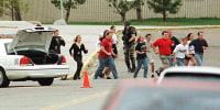 Students run from Columbine High School under cover from police on April 20, 1999, in Littleton, Colo.,