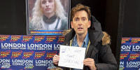 David Tennant with a sign that says, "He's not that special!" behind his son, Ty Tennant.
