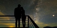 A couple standing on the balcony on the scenic starry sky background.