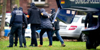 An suspect, second right, is escorted from a police helicopter by police officers after the arrival in Karlsruhe, Germany today. 