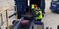 American Airlines baggage handlers load luggage on an airplane at O'Hare International Airport, in Chicago