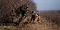 Ukrainian soldiers fire a mortar launcher at a position along the front line in Donetsk region