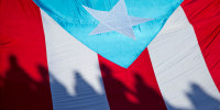 Demonstrators carry a Puerto Rican flag at a "United for Health" march to protest cuts to Medicare and Medicaid funding for the island in 2015.