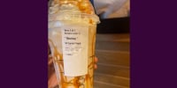 A large starbucks frappuchino with carmel swirls and a sticker with the name * Monkey * on it.