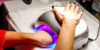 Woman's hand in a lamp for manicure. Dries nails after polishing.