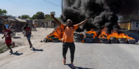 Image: A man gestures and shouts by a burning tires barricade during a police demonstration after a gang attack on a police station in Port-au-Prince, Haiti.