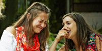 Two women laughing together at dining table.