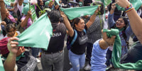 Feminist demonstrators wave green scarves during a demonstration on International Safe Abortion Day