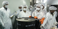 Iranian technicians remove a container of radioactive uranium, 'yellow cake', sealed by the International Atomic Energy Agency, to be used at the Isfahan Uranium Conversion Facilities
