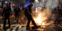 A French gendarme kicks a street fire during a demonstration in Paris