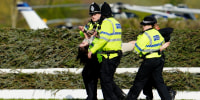 Members of the police forces remove a protester before the start of a Grand National horse race