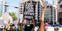 Abortion rights activists wave signs while protesting on a street corner in Fort Lauderdale, Fla.