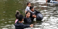 Migrants cross the Rio Grande in Matamoros, Mexico while traveling to the United States border
