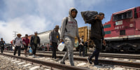Inmigrantes caminan después de desembarcar de un tren de carga en ruta a la frontera entre Estados Unidos y México el 10 de mayo de 2023 cerca de Ciudad Juárez, México.